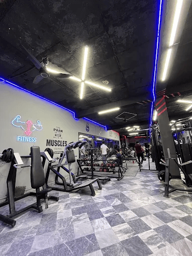 Machines along the wall with the neon Fitness sign